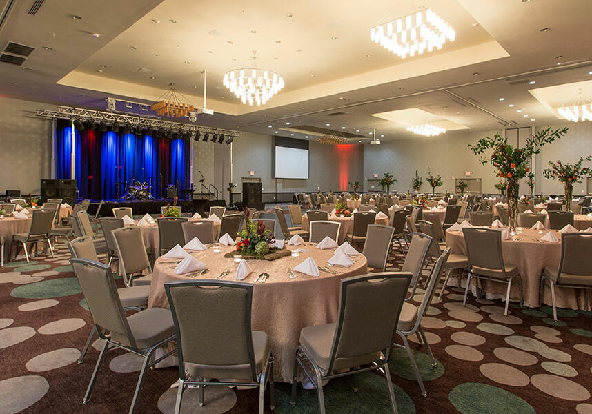 convention center space with round tables and chairs as well as a stage